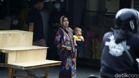 Seorang ibu menggendong anaknya tanpa memakai masker saat berada di tempat umum, di Jalan Raya Hankam, Pondok Gede, Kota Bekasi.