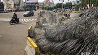 Sebagian kawat berduri telah dipasang melintang. Namun sebagian lagi masih diletakkan di pinggir jalan.