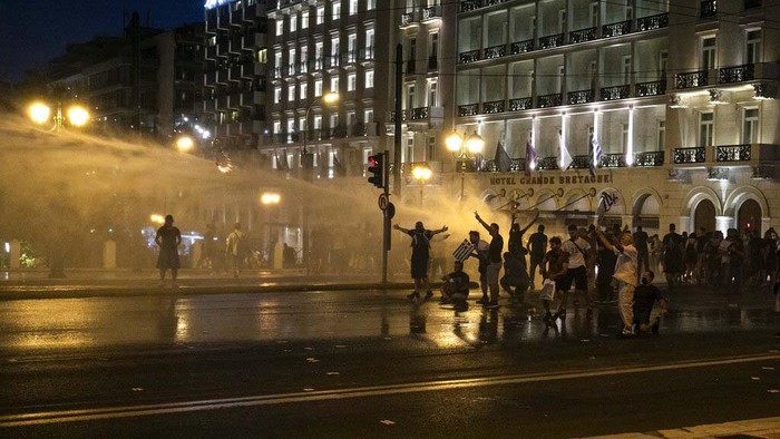 Demo Tolak Vaksinasi COVID-19 di Yunani Rusuh Greek police secure an area as anti-vaccine protesters throw flares and petrol bombs during a rally at Syntagma square, central Athens, on Saturday, July 24, 2021. Thousands of people protested against Greek government's measures to curb rising COVID-19 infections and drive up vaccinations in the country where almost 50% of Greeks and country residents have received at least one dose of the vaccine. (AP Photo/Yorgos Karahalis)