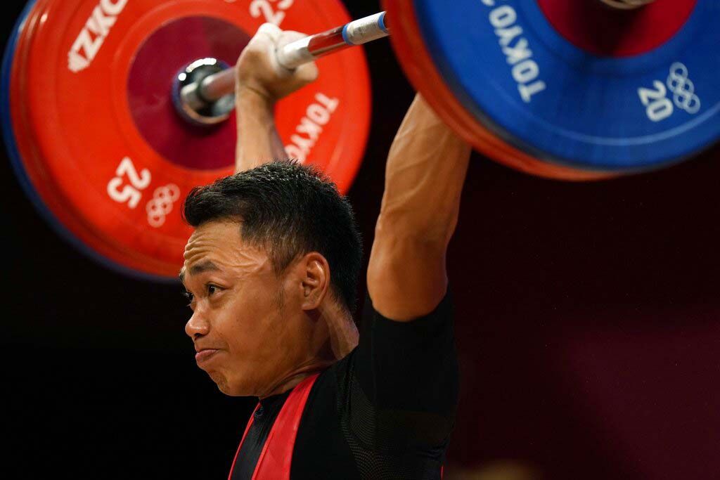 Li Fabin of China , gold medal, right, celebrates on the podium with silver medal Eco Yuli Irawan of Indonesia in the men's 61kg weightlifting event, at the 2020 Summer Olympics, Sunday, July 25, 2021, in Tokyo, Japan. (AP Photo/Luca Bruno)