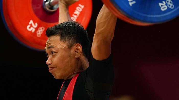 Li Fabin of China , gold medal, right, celebrates on the podium with silver medal Eco Yuli Irawan of Indonesia in the mens 61kg weightlifting event, at the 2020 Summer Olympics, Sunday, July 25, 2021, in Tokyo, Japan. (AP Photo/Luca Bruno)