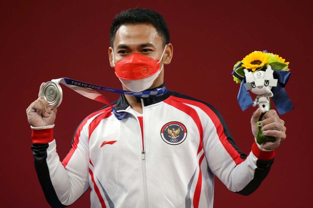 Li Fabin of China , gold medal, right, celebrates on the podium with silver medal Eco Yuli Irawan of Indonesia in the men's 61kg weightlifting event, at the 2020 Summer Olympics, Sunday, July 25, 2021, in Tokyo, Japan. (AP Photo/Luca Bruno)