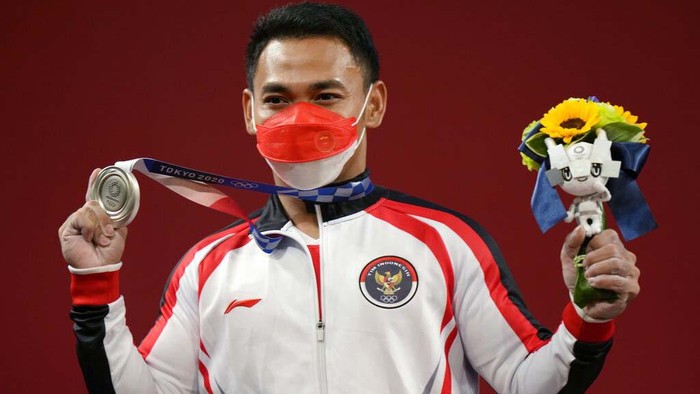 Li Fabin of China , gold medal, right, celebrates on the podium with silver medal Eco Yuli Irawan of Indonesia in the men's 61kg weightlifting event, at the 2020 Summer Olympics, Sunday, July 25, 2021, in Tokyo, Japan. (AP Photo/Luca Bruno)