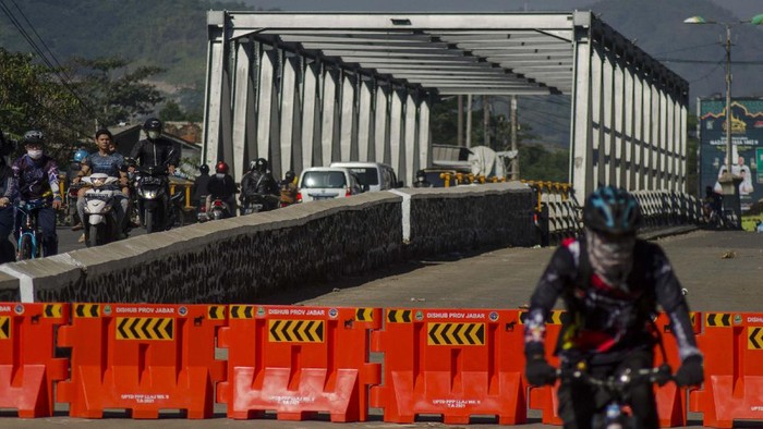 Sejumlah pengendara melintas pada sisi jalur Jembatan Sungai Citarum yang ditutup di Jalan Raya Dayeuhkolot, Kabupaten Bandung, Jawa Barat, Minggu (25/7/2021). Jembatan yang menjadi salah satu akses penguhubung jalan Kota Bandung dan Kabupaten Bandung tersebut mengalami keretakkan pada bagian bawah sehingga terpaksa ditutup dan arus lalu lintas dialihkan sementara untuk selanjutnya dilakukan penanganan perbaikan oleh Dinas Bina Marga dan Tata Ruang (DBMTR) Provinsi Jawa Barat dan Dinas Pekerjaan Umum dan Penataan Ruang Kabupaten Bandung . ANTARA FOTO/Novrian Arbi/hp.