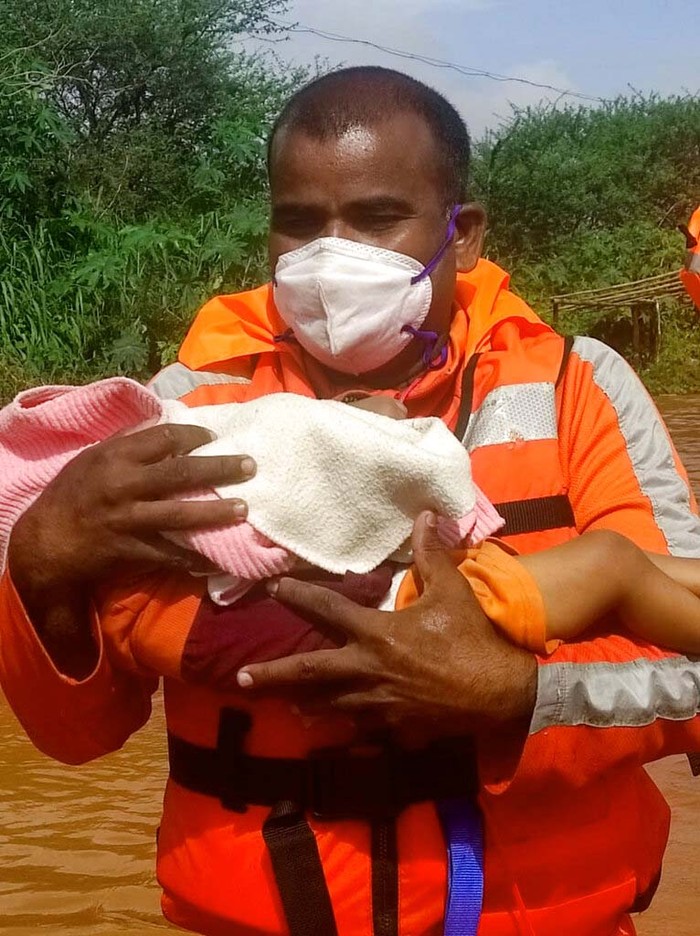 Korban Tewas Akibat Longsor di India Terus Bertambah People stranded in flood waters watch others being rescued at Kolhapur in western Maharashtra state, India, Saturday, July 24, 2021. Officials say landslides and flooding triggered by heavy monsoon rain have killed more than 100 people in western India. More than 1,000 people trapped by floodwaters have been rescued. (AP Photo)