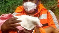 Petugas mengevakuasi balita korban longsor. 