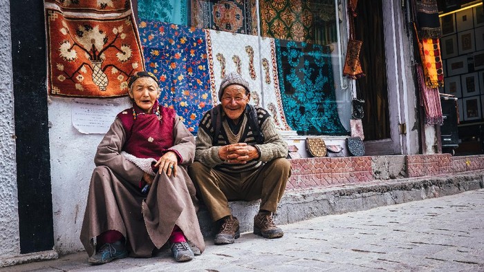 Leh , Ladakh region , India - August 20, 2016: Old Ladakhi people couple carpet sellers sitting on the street in Leh, India