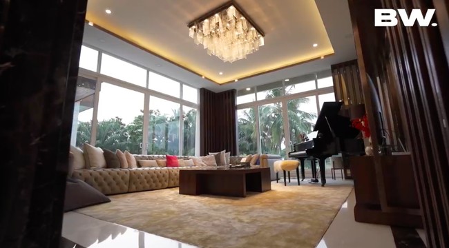 Ruang keluarga tampak cozy dengan sofa panjang yang penuh bantal dan karpet berbahan bulu. Di ruangan ini juga terdapat sebuah grand piano. (Foto: YouTube/Boy William)