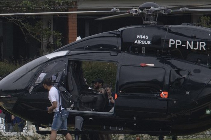Brazil's footballer Neymar (C, inside chopper) arrives with teammates Daniel Alves (foreground) and Thiago Silva (R) in his helicopter the at Granja Comary sport complex in Teresopolis, Brazil, on June 2, 2019 where the national team is training ahead of the Copa America football tournament. (Photo by Mauro PIMENTEL / AFP)
