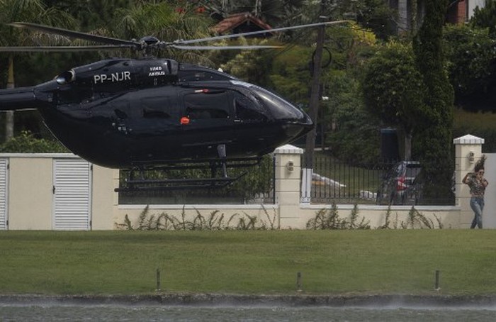 Brazil's footballer Neymar (C, inside chopper) arrives with teammates Daniel Alves (foreground) and Thiago Silva (R) in his helicopter the at Granja Comary sport complex in Teresopolis, Brazil, on June 2, 2019 where the national team is training ahead of the Copa America football tournament. (Photo by Mauro PIMENTEL / AFP)
