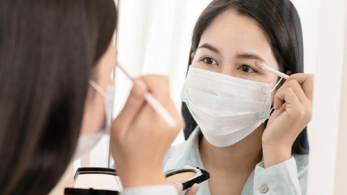 Mirror reflection asian woman wear surgical face mask apply cosmetic make up for go out to work after unlock Coronavirus lockdown. Reopenning , restart, Self-quarantine and social distancing concept.
