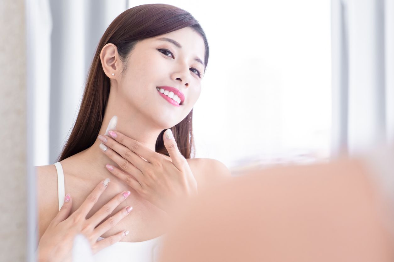 asian  beauty woman apply lotion on her neck in the bathroom