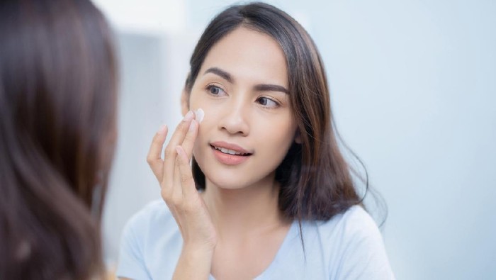 Asian women applying face lotion.