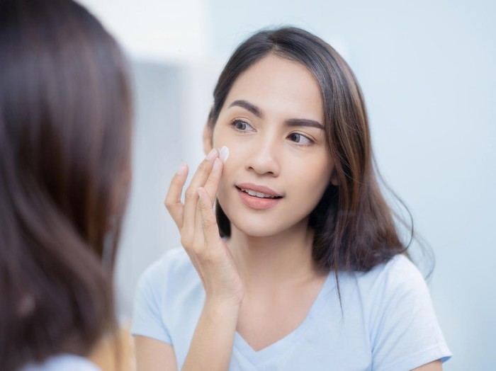 Ilustrasi Sunscreen Asian women applying face lotion.