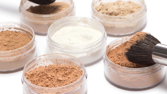 Professional make up products. Jars filled with loose cosmetic powder different shades and makeup brushes on white background