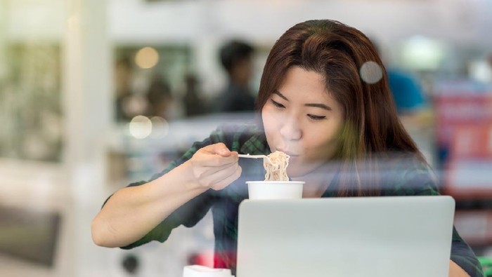 makan terlalu cepat Portrait of asian businesswoman in casual suit eating noodles with happiness action in rush hour at the desk beside the glass in modern office, Business work hard concept