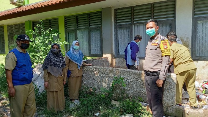 Petugas membersihkan sampah jarum suntik bekas vaksin yang dibuang ke tempat sampah di SMK di Depok (Dok.Istimewa). Foto dikirim Plt Camat Tapos, Anwar.