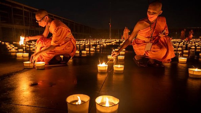 Umat Buddha di Thailand merayakan Hari Asalha Puja di tengah pandemi Corona. Ribuan lilin disiapkan untuk menerangi kuil saat perayaan Asalha Puja.