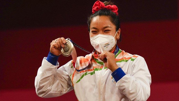 Chanu Saikhom Mirabai of India celebrates on the podium after winning the silver medal in the womens 49kg weightlifting event, at the 2020 Summer Olympics, Saturday, July 24, 2021, in Tokyo, Japan. (AP Photo/Luca Bruno)