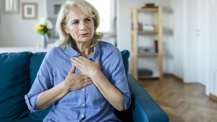 Senior Woman Suffering From Chest Pain While Sitting on Sofa at Home. Old Age, Health Problem, Vision and People Concept. Heart Attack Concept. Elderly Woman Suffering From Chest Pain Indoor