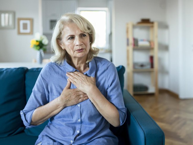 Senior Woman Suffering From Chest Pain While Sitting on Sofa at Home. Old Age, Health Problem, Vision and People Concept. Heart Attack Concept. Elderly Woman Suffering From Chest Pain Indoor