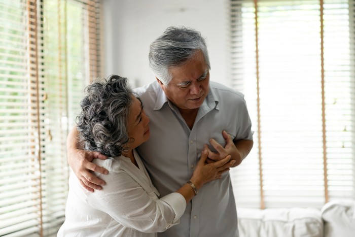 Senior Woman Suffering From Chest Pain While Sitting on Sofa at Home. Old Age, Health Problem, Vision and People Concept. Heart Attack Concept. Elderly Woman Suffering From Chest Pain Indoor