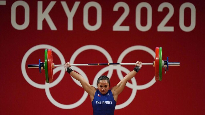 Lifter Filipina Raih Emas Pertama Sepanjang Sejarah Olimpiade Hidilyn Diaz of Philippines celebrates with Weightlifting Philippines federation president Monico Puntuevella after winning the gold medal in the women's 55kg weightlifting event, at the 2020 Summer Olympics, Monday, July 26, 2021, in Tokyo, Japan. (AP Photo/Luca Bruno)