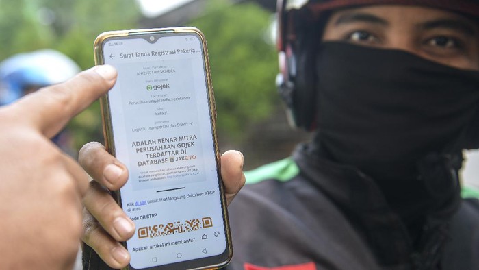 Seorang pengemudi ojek menunjukkan Surat Tanda Registrasi Pekerja (STRP) saat akan memasuki wilayah Jakarta.