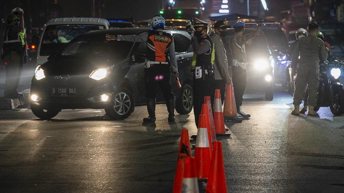 Petugas gabungan mengarahkan mobil untuk memutar balik saat pelaksanaan Pemberlakuan Pembatasan Kegiatan Masyarakat (PPKM) Darurat di Jalan Raya Bogor, Jakarta.