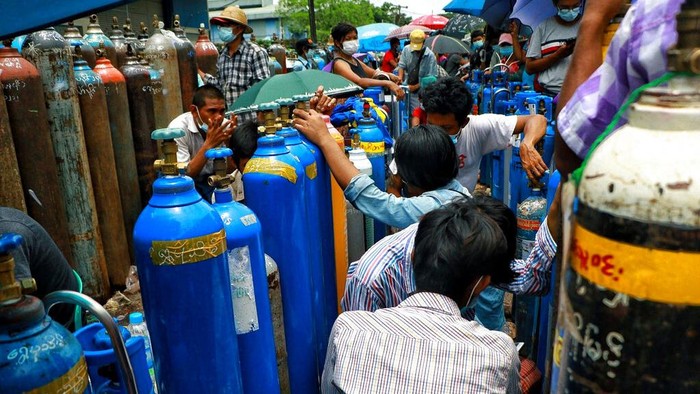 A man holds an oxygen tank while waiting outside the Naing oxygen factory at the South Dagon industrial zone in Yangon, Myanmar, Wednesday, July 28, 2021. Myanmar is currently reeling from soaring numbers of COVID-19 cases and deaths that are badly straining the country’s medical infrastructure.  (AP Photo)