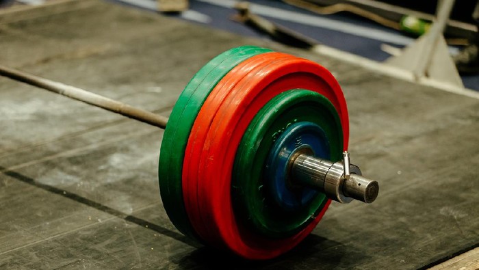 barbell with green and red plates on platform for powerlifting