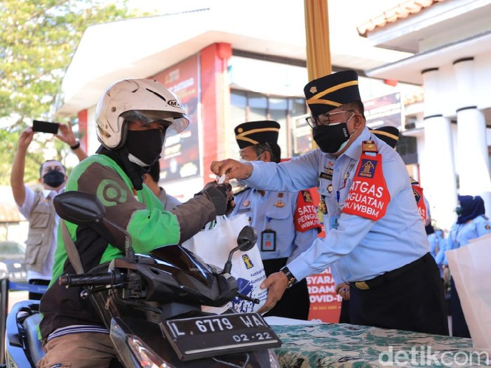Ojol di Surabaya mendapat paket sembako secara drive thru dari KemenkumHam Jatim. Bantuan itu diberikan untuk meringankan beban di tengah pandemi COVID-19.