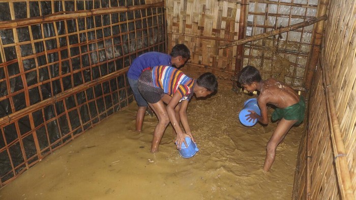 A Rohingya refugee man sits with his child inside his inundated shelter following heavy rains at the Rohingya refugee camp in Kutupalong, Bangladesh, Wednesday, July 28, 2021. Days of heavy rains have brought thousands of shelters in various Rohingya refugee camps in Southern Bangladesh under water, rendering thousands of refugees homeless. (AP Photo/ Shafiqur Rahman)