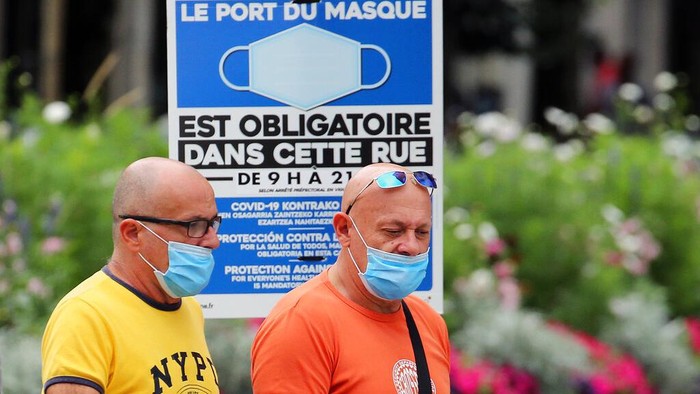 People wearing face masks to protect against coronavirus walk on the pedestrian promenade along the beach in Biarritz, southwestern France, Wednesday, July 28, 2021. Local authorities in France are re-imposing mask mandates and other virus restrictions because of fast-growing infections with the delta variant, which is causing COVID-19 hospitalizations in France to rise again. (AP Photo/Bob Edme)