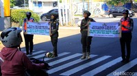 Empat orang petugas pun membentangkan spanduk berisi imbauan dihadapan para pengendara. Sementara petugas dari Satpol PP lainnya membagikan masker kepada pengendara dan pesepeda.