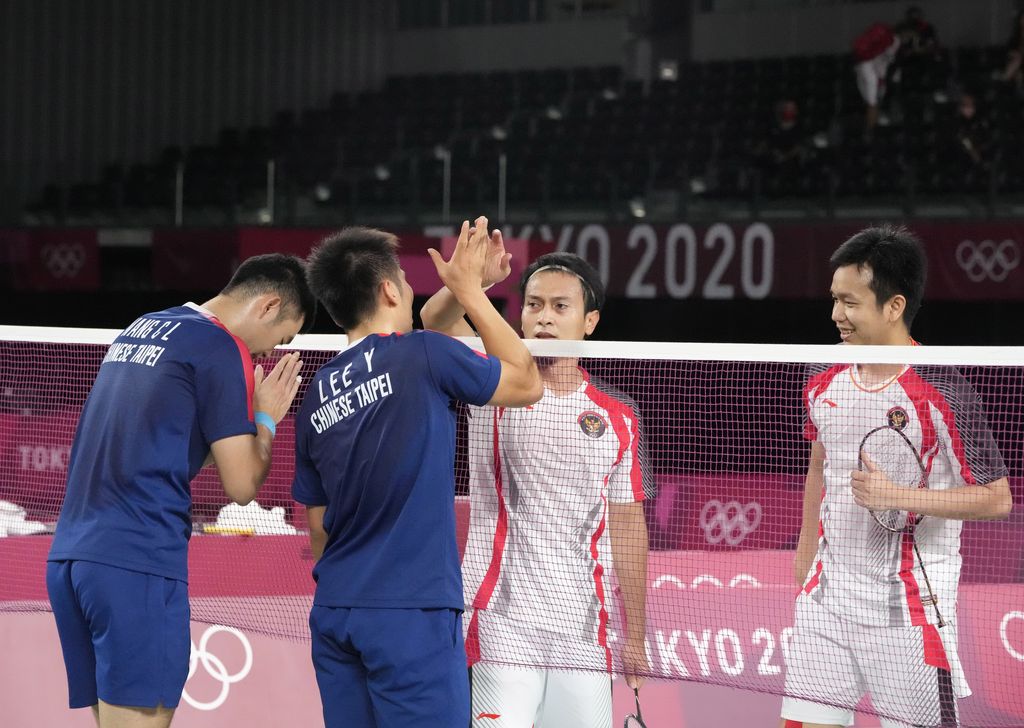 Taiwan's Lee Yang, left, and Wang Chi-Lin talk to Indonesia's Mohammad Ahsan and Hendra Setiawan after wining their men's doubles badminton semifinal match at the 2020 Summer Olympics, Friday, July 30, 2021, in Tokyo, Japan. (AP Photo/Dita Alangkara)