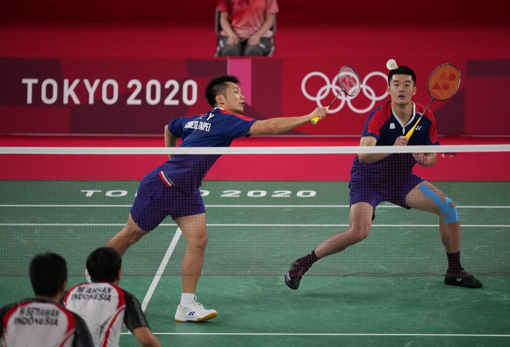 Taiwan's Lee Yang, left, and Wang Chi-Lin talk to Indonesia's Mohammad Ahsan and Hendra Setiawan after wining their men's doubles badminton semifinal match at the 2020 Summer Olympics, Friday, July 30, 2021, in Tokyo, Japan. (AP Photo/Dita Alangkara)
