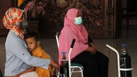 Seorang ibu ikut mengantre dengan menggendong anaknya.