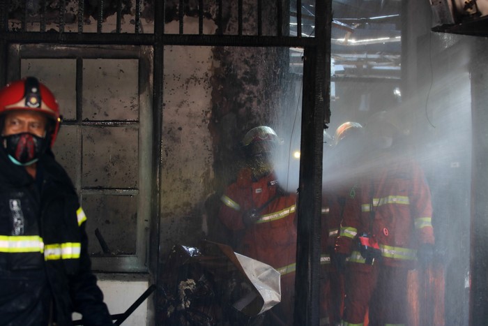 Petugas Dinas Pemadam Kebakaran Kota Surabaya melakukan pembasahan rumah yang terbakar di Perumahan Dosen Institut Teknologi Sepuluh Nopember (ITS) Surabaya, Jawa Timur, Jumat (30/7/2021). Sebanyak 12 unit kendaraan pemadam kebakaran dari Dinas Pemadam Kebakaran Kota Surabaya dikerahkan untuk memadamkan kebakaran yang menelan satu korban jiwa tersebut. ANTARA FOTO/Didik Suhartono/aww.