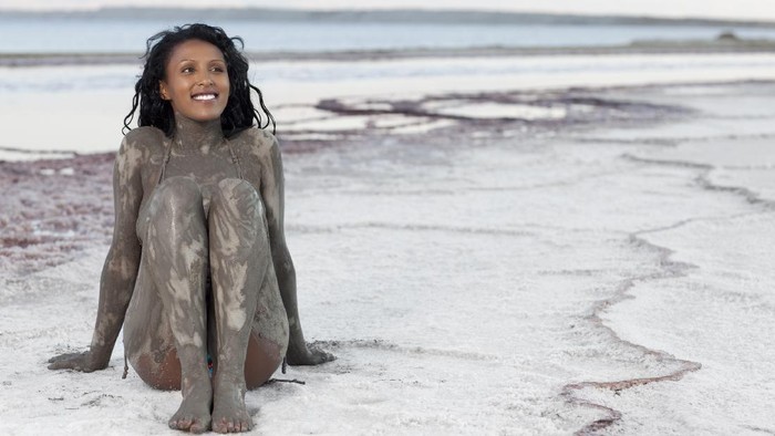 Laut mati, dead sea Attractive woman on Dead sea beach. Her body wrapped in some of the most exotic natural mineral-rich mud.