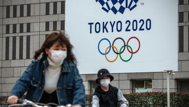 Olimpiade Tokyo Logo TOKYO, JAPAN - MARCH 13: People cycle past a banner for the Tokyo Olympics on March 13, 2020 in Tokyo, Japan. Excluding the Diamond Princess cruise ship cases, the number of coronavirus infections in Japan reached 684 today as United States President Donald Trump suggested the Tokyo Olympics should be postponed to next year. (Photo by Carl Court/Getty Images)
