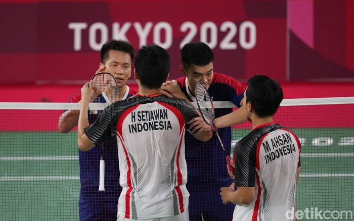 Taiwan's Lee Yang, left, and Wang Chi-Lin talk to Indonesia's Mohammad Ahsan and Hendra Setiawan after wining their men's doubles badminton semifinal match at the 2020 Summer Olympics, Friday, July 30, 2021, in Tokyo, Japan. (AP Photo/Dita Alangkara)