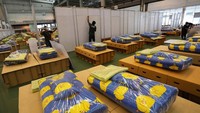 Para pekerja mengebor dinding untuk instalasi toilet dan menyiapkan tempat tidur beserta selimutnya.