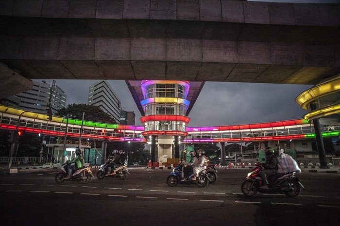 Seorang perempuan duduk di atas pembatas jalan di dekat halte Centrale Stichting Wederopbouw (CSW) yang berhiaskan lampu warna-warni di Kawasan Kebayoran Baru, Jakarta, Sabtu (31/7/2021). Proyek pembangunan jembatan penghubung atau skybridge untuk intergrasi Halte Transjakarta CSW dengan Stasiun MRT ASEAN itu mengusung konsep desain Cakra Selaras Wahana yang memiliki arti sebagai lingkaran penghubung yang setara antar moda. ANTARA FOTO/Aprillio Akbar/wsj.