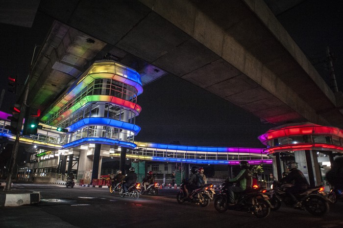 Seorang perempuan duduk di atas pembatas jalan di dekat halte Centrale Stichting Wederopbouw (CSW) yang berhiaskan lampu warna-warni di Kawasan Kebayoran Baru, Jakarta, Sabtu (31/7/2021). Proyek pembangunan jembatan penghubung atau skybridge untuk intergrasi Halte Transjakarta CSW dengan Stasiun MRT ASEAN itu mengusung konsep desain Cakra Selaras Wahana yang memiliki arti sebagai lingkaran penghubung yang setara antar moda. ANTARA FOTO/Aprillio Akbar/wsj.