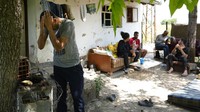 Para migran beristirahat di depan sebuah rumah kosong  di desa Majdan, Serbia. Majdan sering menjadi lokasi para imigran yang mayoritas dari kawasan Timur Tengah.