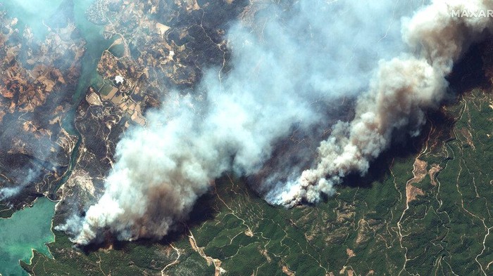 Smoke rises from a forest fire, threatening a residential area in the Aegean coastal town of Bodrum, Turkey, Thursday, July 29, 2021. Turkish authorities on Thursday began investigating the cause of a string of forest fires in Turkeys Mediterranean and southern Aegean regions, including two near the coastal resort town of Manavgat that killed three people and sent over 50 others to hospitals as homes burned down. (IHA via AP)
