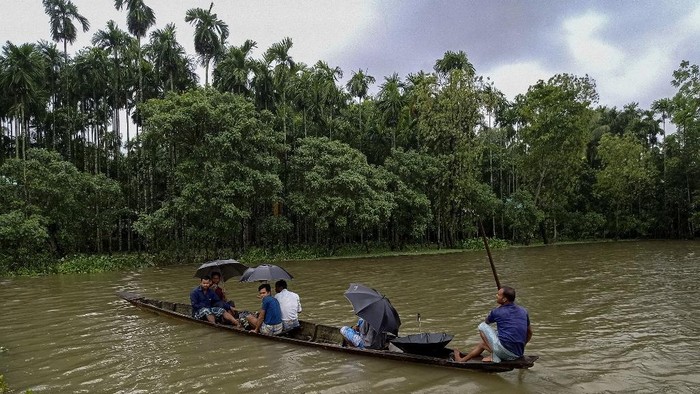 Locals use a boat to reach towards a shelter after their houses were submerged in flood waters at Maulovir Para, Coxs Bazar on July 30, 2021 after monsoon floods and landslides have cut off more than 300,000 people in villages across southeast Bangladesh and killed at least 20 people including six Rohingya refugees. (Photo by Tanbir MIRAJ / AFP)