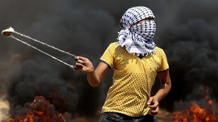 A Palestinian uses a slingshot to hurl stones during clashes with Israeli forces in the village of Beita in the north of the occupied West Bank on July 30, 2021. (Photo by JAAFAR ASHTIYEH / AFP)