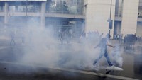 Seorang demonstran menendang tabung gas di tengah aksi unjuk rasa memprotes kebijakan wajib memiliki paspor COVID-19 yang berujung ricuh di kawasan Paris, Prancis. AP Photo/Adrienne Surprenant. 